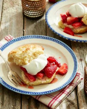 Frittelle di fragole al brandy con panna montata al malto su un piatto su un tavolo di legno