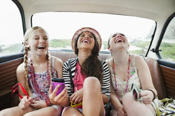 tre ragazze che ridono sul sedile posteriore di un veicolo