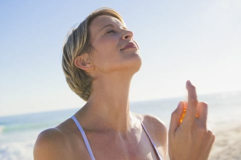 Profumo di spruzzatura della donna sul suo collo sulla spiaggia