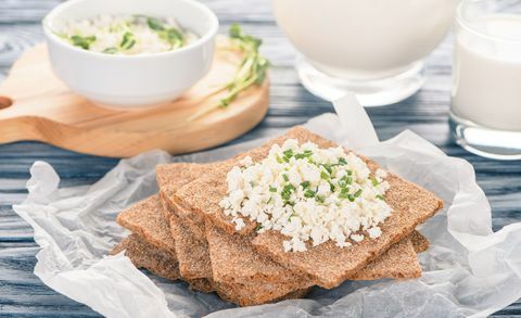 vista ravvicinata di cracker croccanti con topping di ricotta sul tavolo di legno