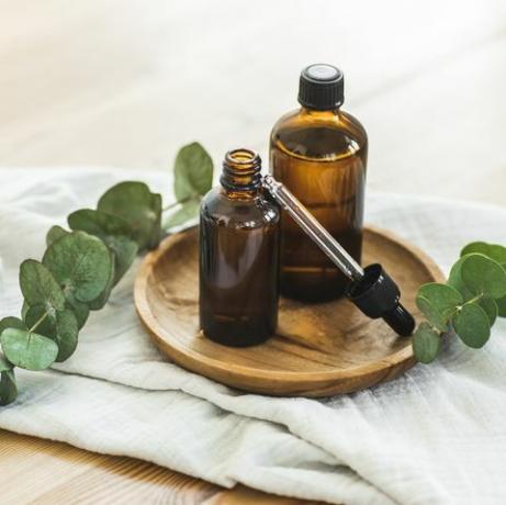 varie bottiglie di vetro ambrato per cosmetici, medicina organica naturale, oli essenziali o altri liquidi su legno piatto vicino a fiale in tessuto di mussola ed eucalipto con pipetta per oli essenziali, profumi e prodotti per la cura della pelle sostanze