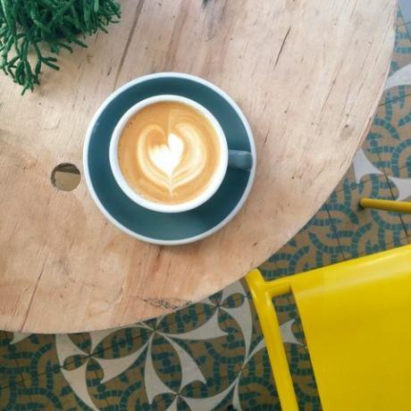 Tazza di caffè con schiuma cuore in tazza verde acqua sul tavolo di legno