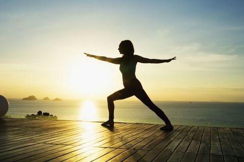 Donna che fa yoga in riva al mare al tramonto