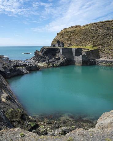caratteristica ben nota nel parco nazionale della costa del Pembrokeshire una vecchia cava inondata dal mare per creare una piscina blu intenso resti di vecchi edifici vicino all'acqua