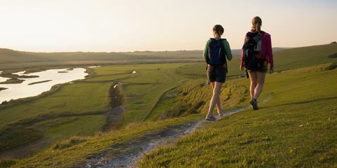 Due donne che fanno un'escursione su una collina verso il tramonto
