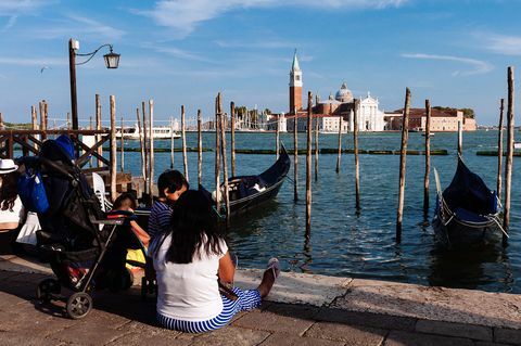 I turisti si siedono a terra a Venezia mentre guardano sopra la Chiesa di San Giorgio