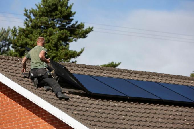 h0chn1 uomo che installa una serie di pannelli solari sul tetto di un impianto domestico di pannelli solari nel Regno Unito