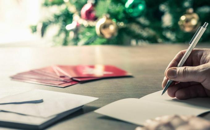scrivere messaggi di cartoline di Natale davanti a un albero di vacanza