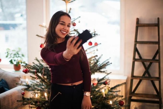 donna che prende un selfie davanti a un albero di Natale