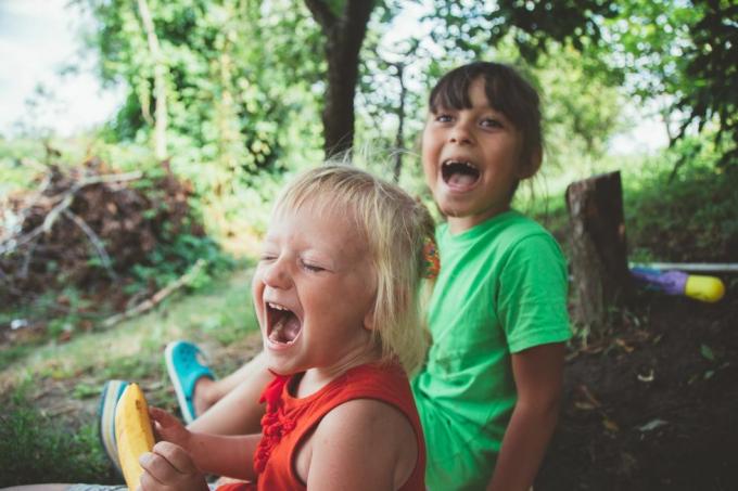 la bambina sorridente felice bionda ha eccitato la risata le mani in bocca