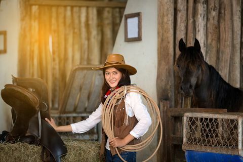 donne vestite in costume da cowboy con cavallo sullo sfondo