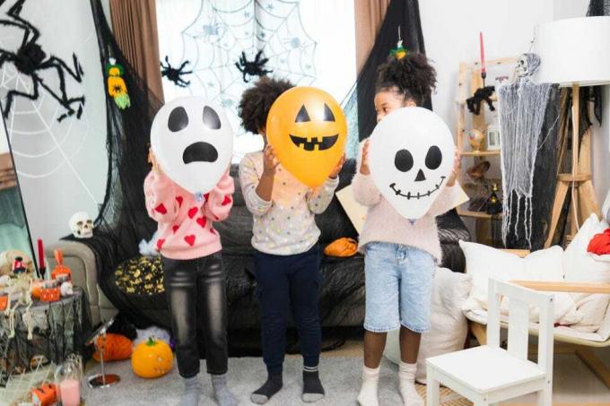 felici bambini caucasici bianchi e africani americani che fanno festa di halloween nella loro casa