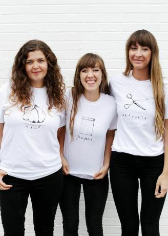 tre donne in magliette bianche, con sasso, carta o forbici scritte e raffigurate sulla maglietta