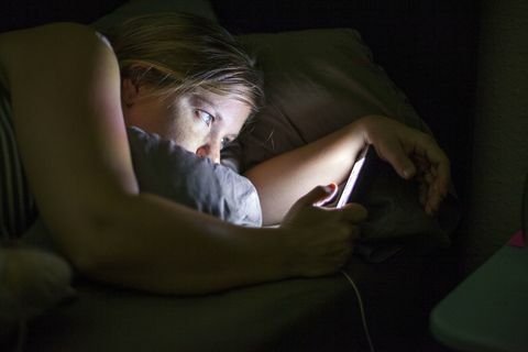 Donna che esamina Smart Phone a letto