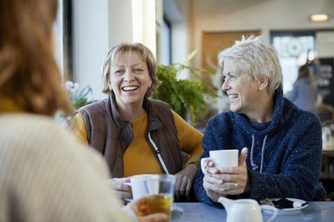 coppia lesbica e figlia adulta che bevono caffè e parlano nella caffetteria