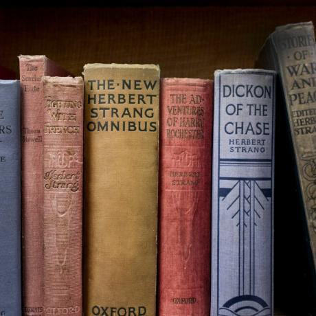 sette libri allineati su uno scaffale della libreria di baratto di seconda mano