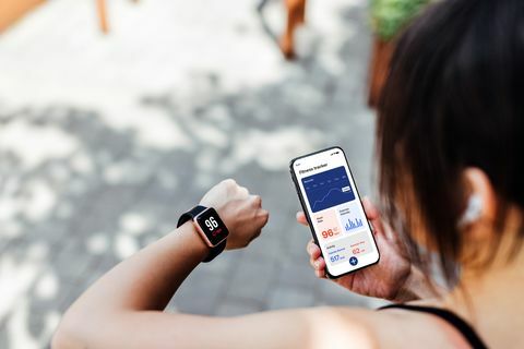 giovane donna che utilizza l'app fitness tracker su smartwatch e smartphone