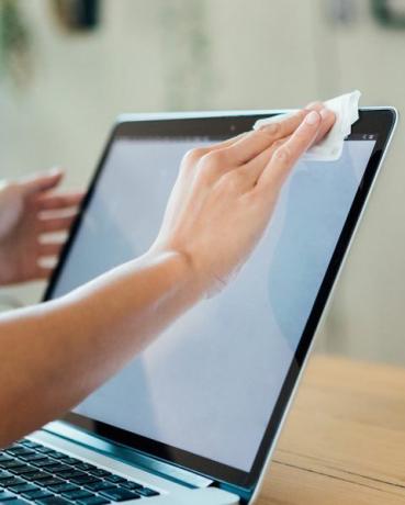 foto ritagliata di una donna che pulisce la superficie del laptop con un panno per la pulizia