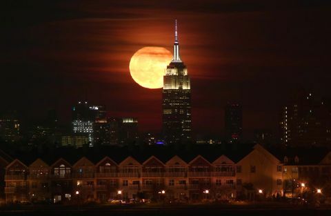 La luna piena sorge dietro l'Empire State Building a New York City