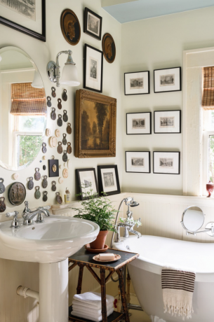 bagno raccolto con opere d'arte vintage alle pareti e vasca con piedini