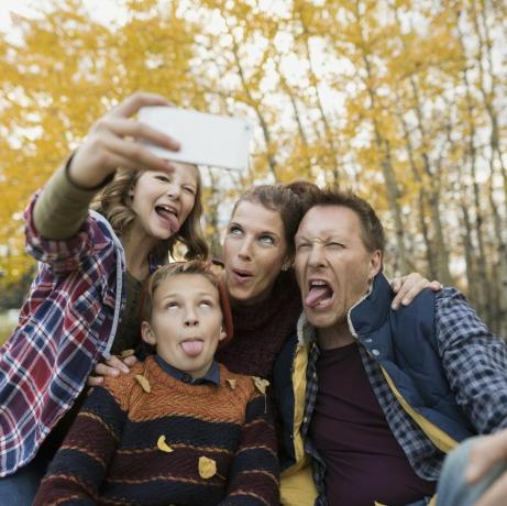 Famiglia sciocca che prende selfie che fa i fronti del parco di autunno