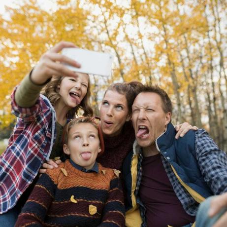 Famiglia sciocca che prende selfie che fa i fronti del parco di autunno