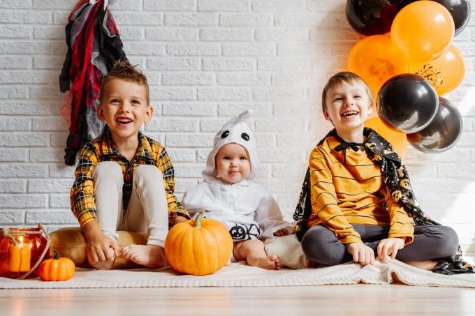i bambini in costume celebrano il muro di mattoni bianco di halloween con lo spazio della copia delle decorazioni