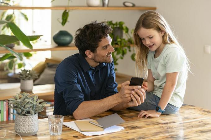 uomo che mostra lo smartphone alla figlia mentre discute a casa